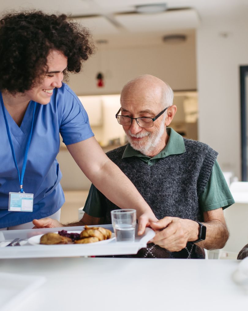 Elderly couple smiling in a calm residential care home setting